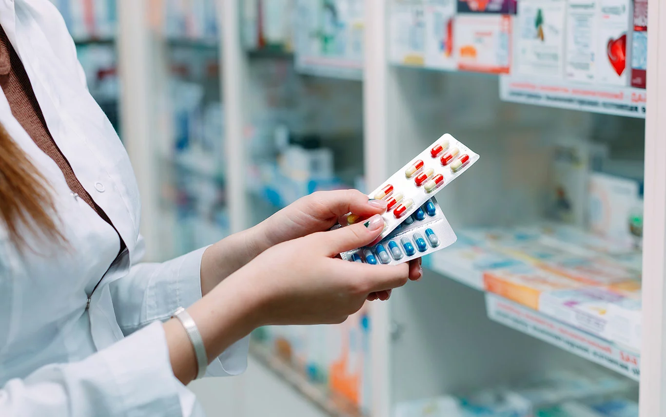 Woman holding two packs of prescription pills 